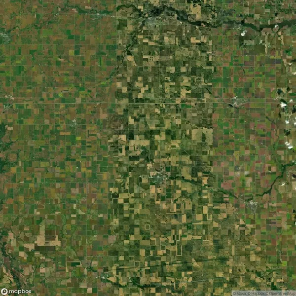 Aerial view of a vast agricultural landscape with a patchwork pattern of green and brown fields, intersected by roads.