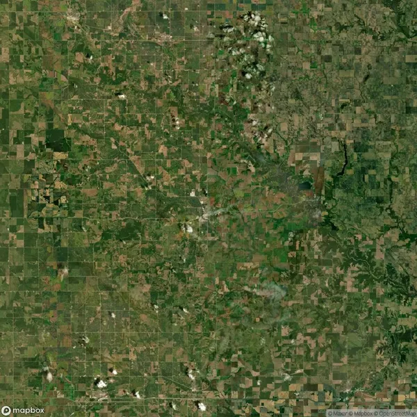 Aerial view of a patchwork landscape with fields, roads, and scattered greenery, showing a mix of agricultural and natural areas.