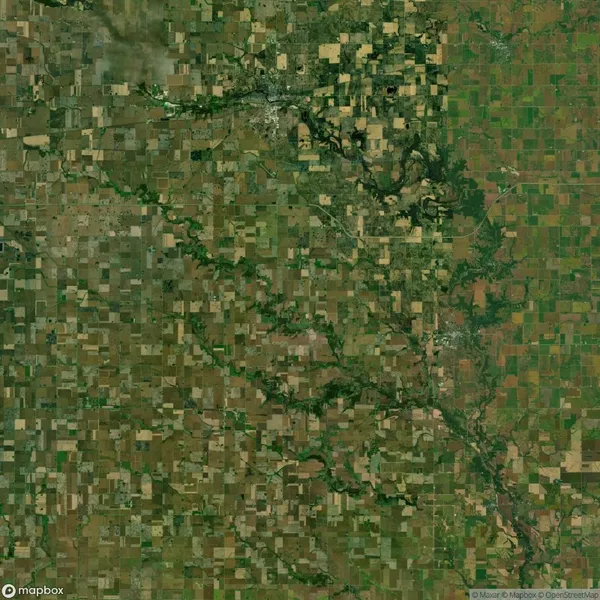 Aerial view of a patchwork landscape with fields, green areas, and a winding river cutting through the center.