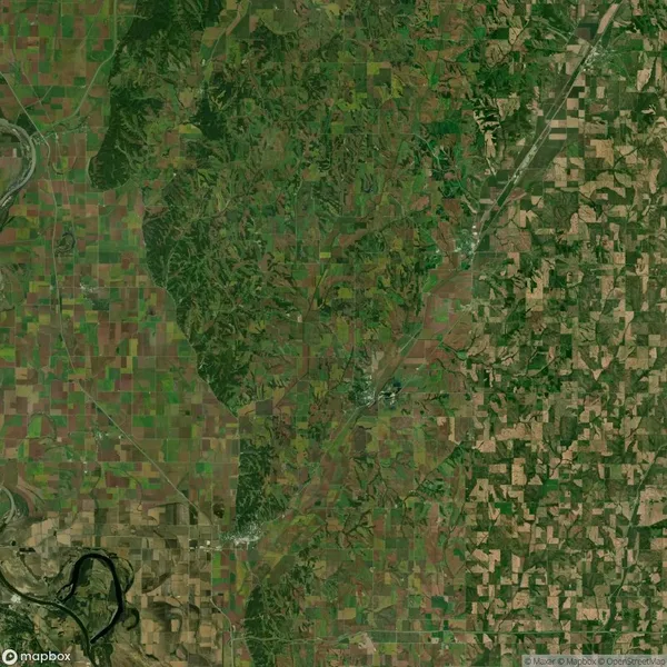 Satellite view of a landscape featuring a patchwork of agricultural fields, a winding river at the lower left, and forested areas interspersed throughout.