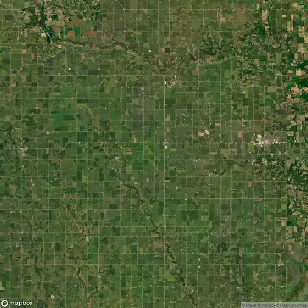 Aerial view of a vast grid-like patchwork of agricultural fields in various shades of green and brown.
