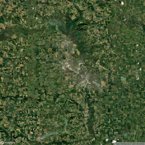 Aerial view of a large, sprawling city surrounded by green agricultural fields, with a river winding through the top right corner.