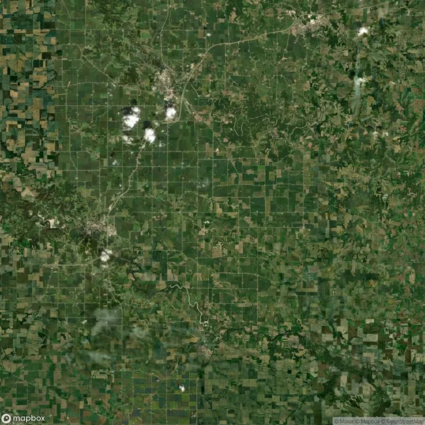 Satellite view of a large agricultural landscape with fields and patches of forest. A river runs through the center, and some clouds are visible in the sky.