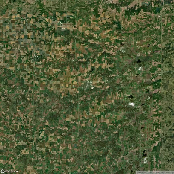Aerial view of a rural landscape with patchwork fields, roads, and scattered greenery.