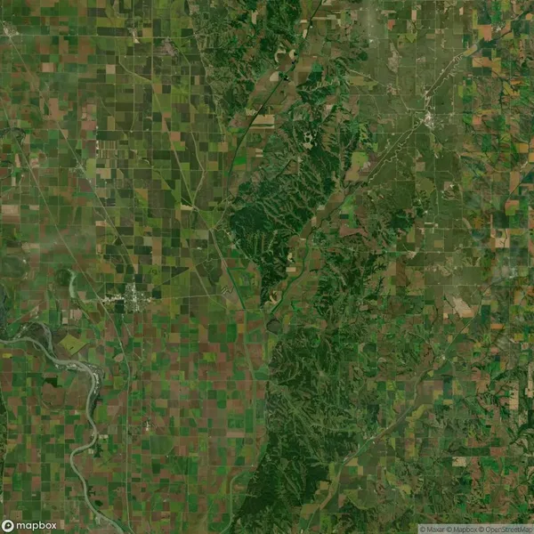 Aerial view of a landscape with a mix of agricultural fields and wooded areas, intersected by a river winding from the bottom left to the center.