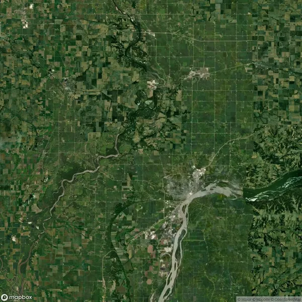 Satellite view of a landscape featuring a mix of farmlands, a river winding through the area, and scattered urban development in the lower central part of the image.