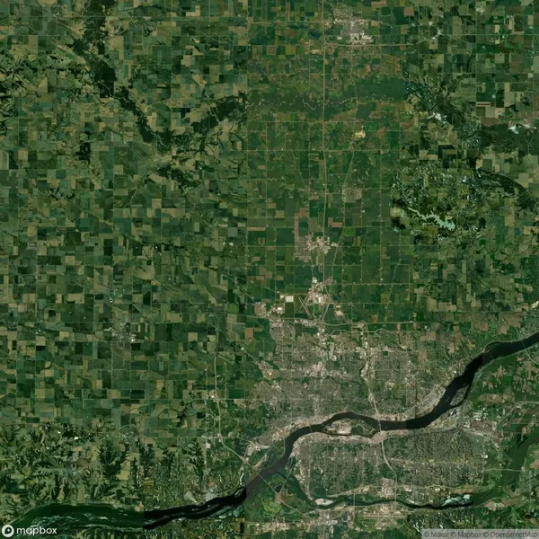 Satellite image showing a patchwork of farmlands and a river passing through an urban area in North Dakota, USA.