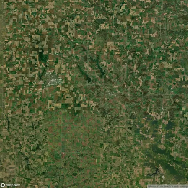 Aerial view of a vast, patchwork landscape with green and brown fields interspersed with irregular natural areas.