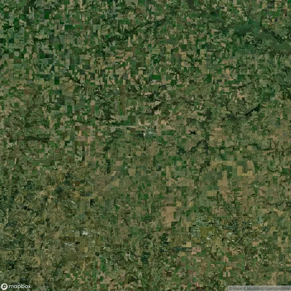 Aerial view of a large patchwork of green and brown agricultural fields and grid-like patterns of farmland.