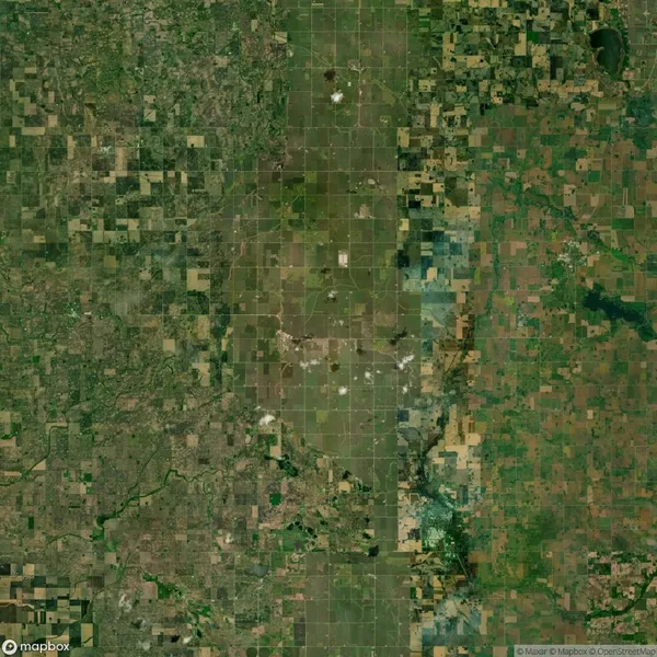Aerial view of a patchy landscape with a mix of green and brown fields. The area is divided into a grid-like pattern with roads or boundaries, depicting an agricultural region.
