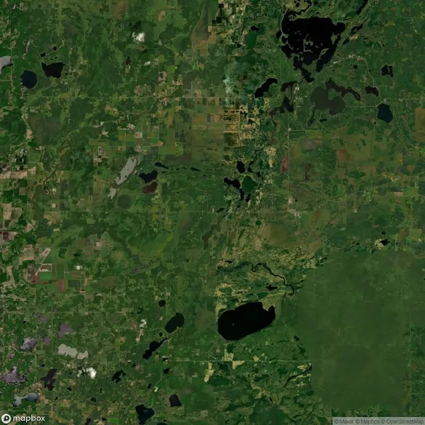 Aerial view of a lush, green landscape with scattered lakes and patches of forested areas. Agricultural fields and roads are visible throughout the scene.