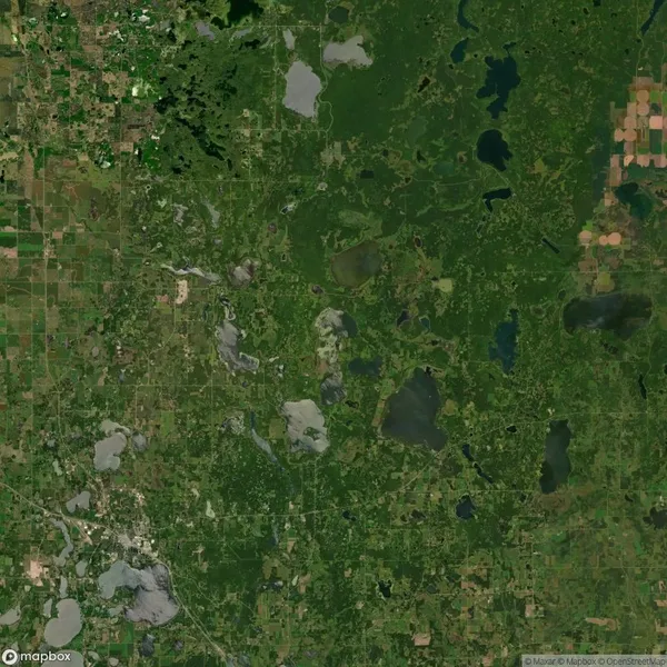 Aerial view of a vast green landscape with patches of water, fields, and sparse settlements scattered across the area.
