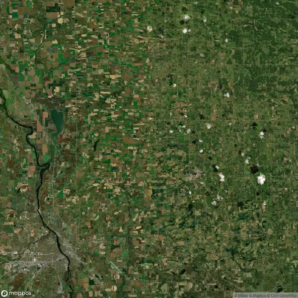 Satellite image showing a landscape with a river on the left, a city area below, and a vast patchwork of agricultural fields on both sides. Sparse white clouds are scattered throughout.