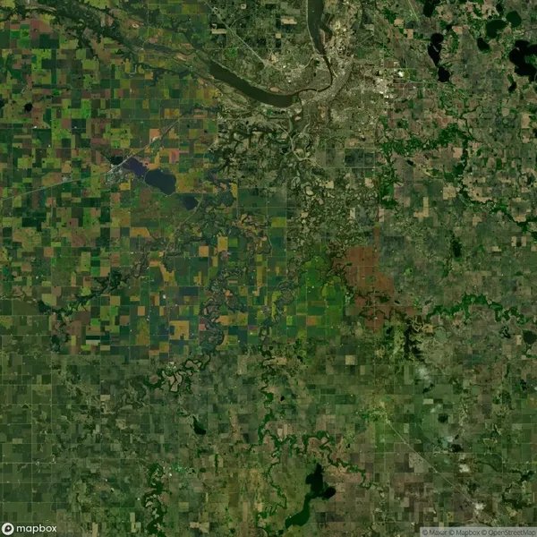 Satellite view of a landscape showing agricultural fields with varied rectangular plots on the left and a river with urban area on the top right.