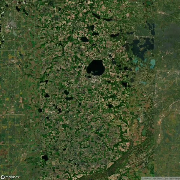 Aerial view of a large green and brown landscape with scattered lakes and irregular patches of vegetation, showing a mix of agricultural and natural areas.