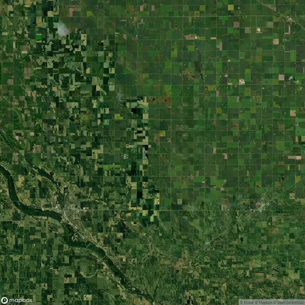 Aerial view of vast farmland with a patchwork of green fields and crops, a winding river in the bottom left corner, and patches of forested areas.
