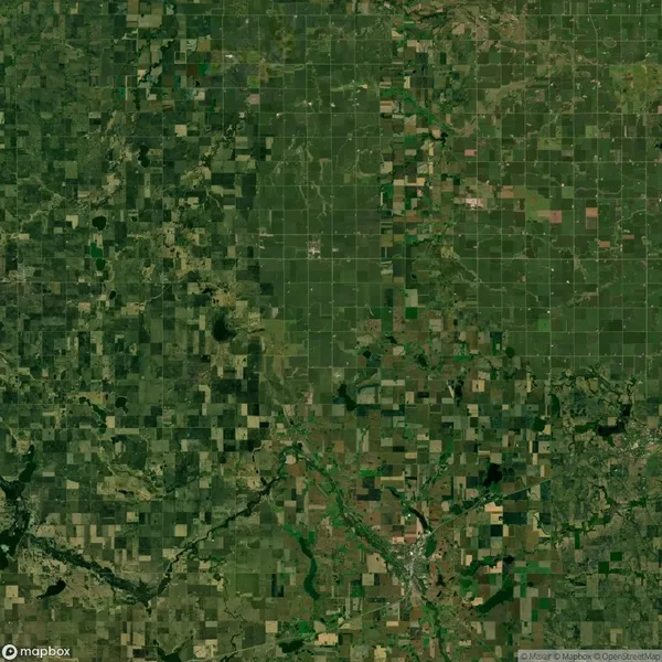 Aerial view of a patchwork landscape with varying shades of green and brown fields and a network of roads, typical of agricultural land.