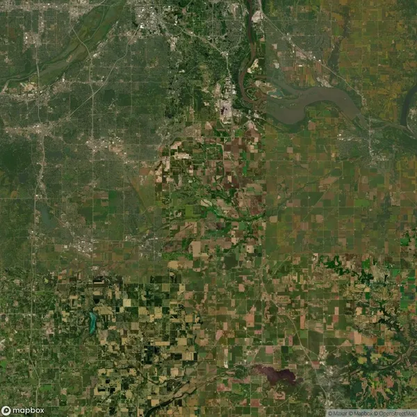 Aerial view of a landscape with a mix of urban and rural areas, showing roads, fields, and a river running through the top right section.