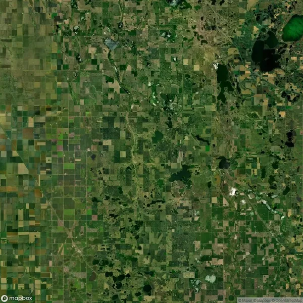 Aerial view of a patchwork landscape with fields, forests, and scattered lakes in a rural area.