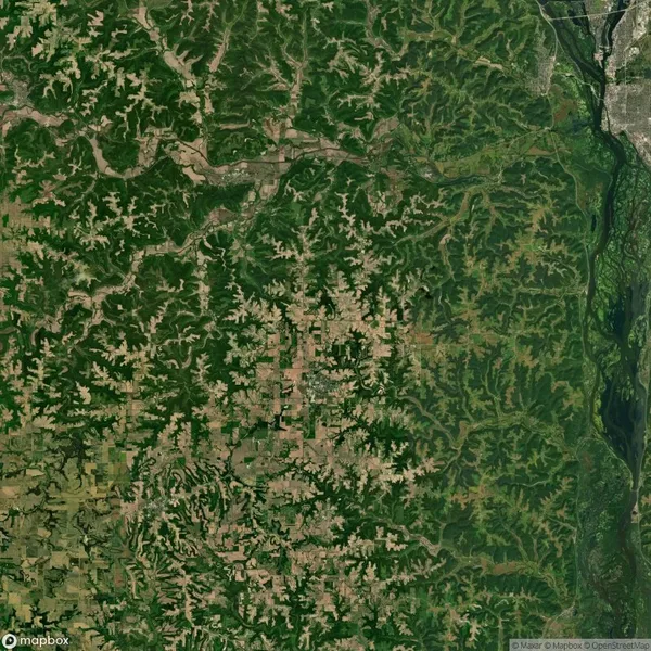 Aerial view of a landscape with dense green forests, waterways, and patches of agricultural land.
