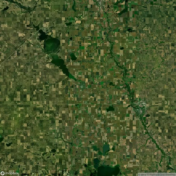 Aerial view of a large agricultural region with patchwork fields, bodies of water, and a meandering river running through the landscape.
