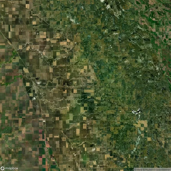 Aerial view of a patchwork agricultural landscape, showing a mix of green and brown rectangular plots surrounded by a network of roads.