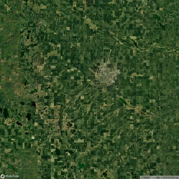 Satellite view of a city surrounded by a patchwork of farmland. The city appears centrally located with roads extending outward into the agricultural landscape.