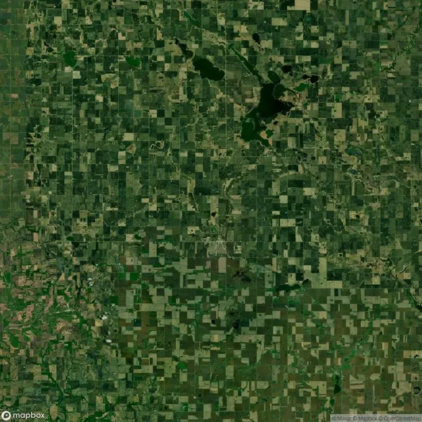 Aerial view of a rural landscape with a grid-like pattern of fields, roads, and scattered green patches.