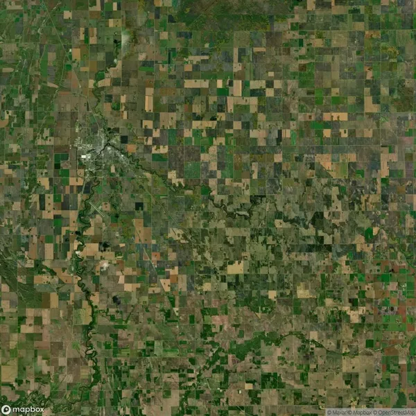 Aerial view of a patchwork of agricultural fields and a winding river in a rural landscape, with a small town visible in the upper left corner.