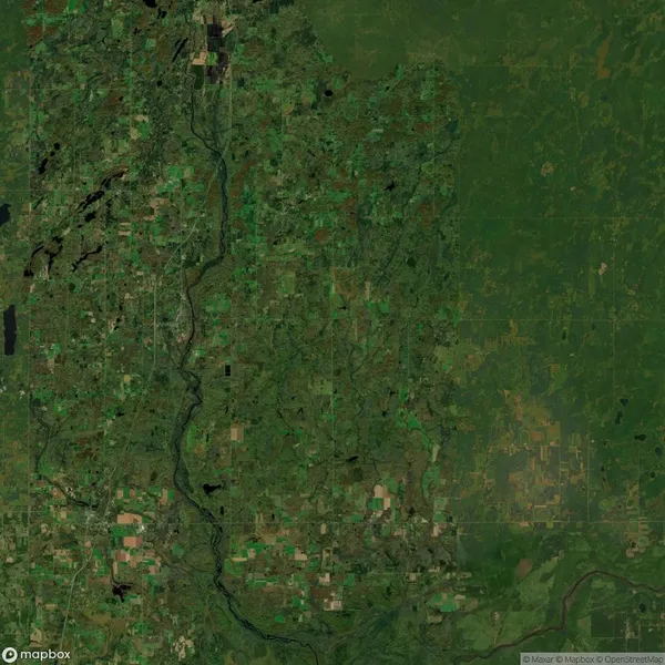 Satellite image of a green and brown landscape featuring forests, fields, and a winding river. Sparse road networks and scattered water bodies are visible.