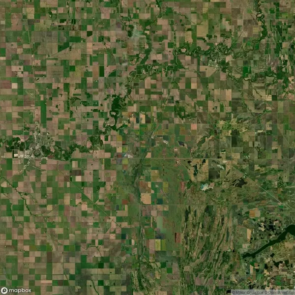 Aerial view of a rural landscape with a patchwork of agricultural fields, winding river, and varying shades of green and brown.