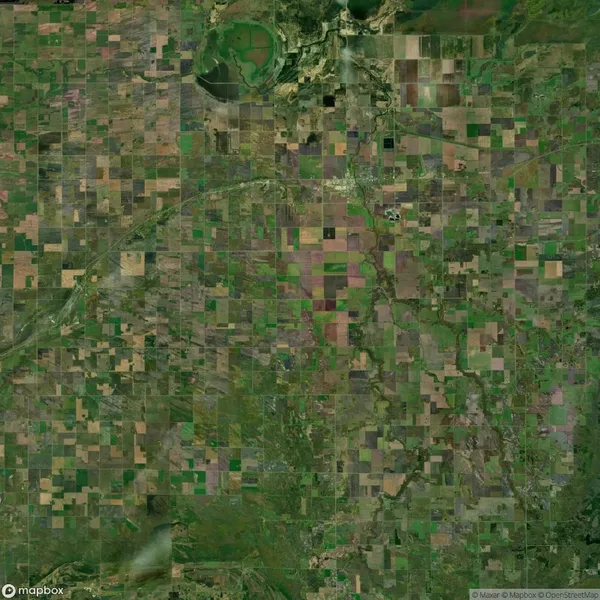 Aerial view of patchwork agricultural fields, showing a mix of green and brown squares divided by roads and irrigation canals.