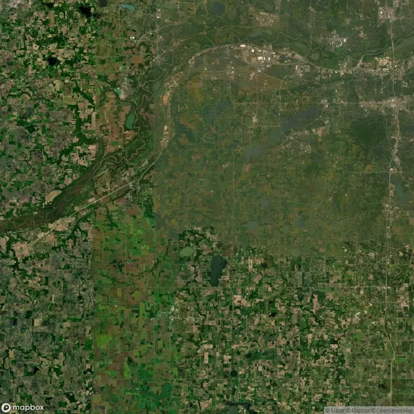 Satellite image showing a landscape with a river winding through the terrain. There are patches of green farmland and urban areas scattered throughout.