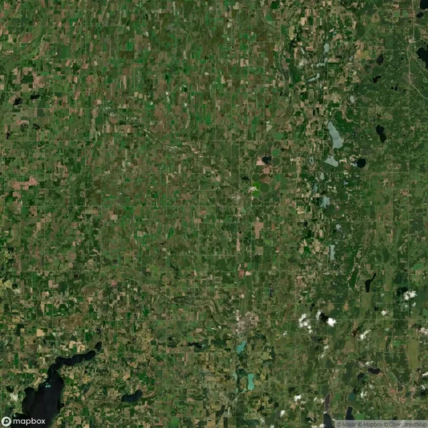 Aerial view of a rural landscape with a patchwork of green fields, scattered small bodies of water, and a few forested areas.