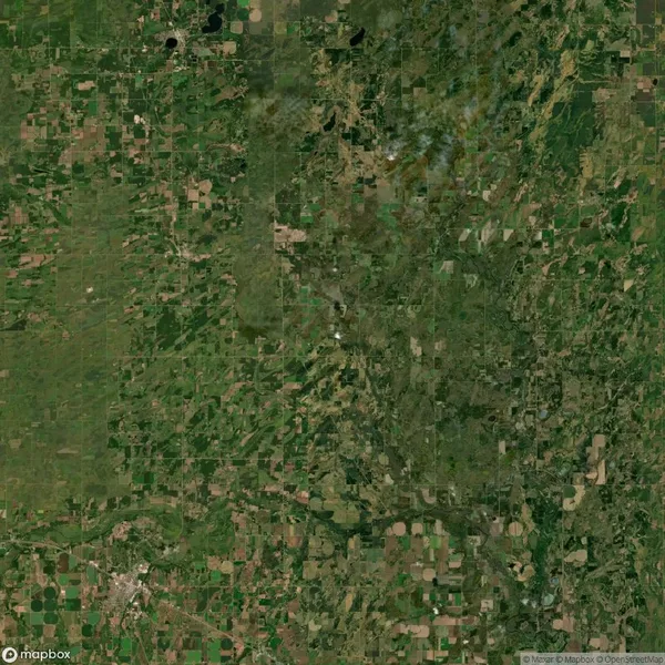 Satellite image depicting a vast patchwork of agricultural fields and natural greenery in a rural landscape, with some roads and small settlements interspersed.