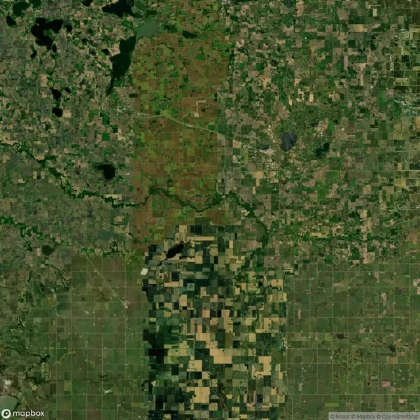 Aerial view of a patchwork landscape featuring lush green fields, brown patches, and small bodies of water, indicating a mix of farmland and natural areas.