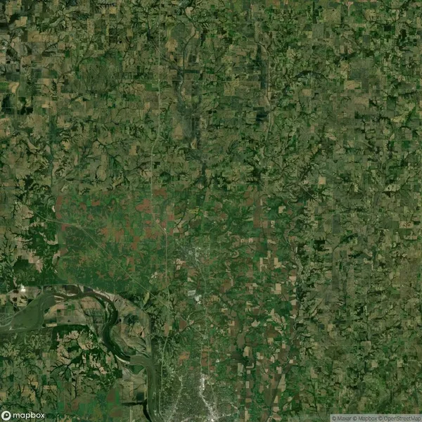 Aerial view of a rural landscape with a patchwork of green and brown fields, intersected by a winding river in the bottom left quadrant.