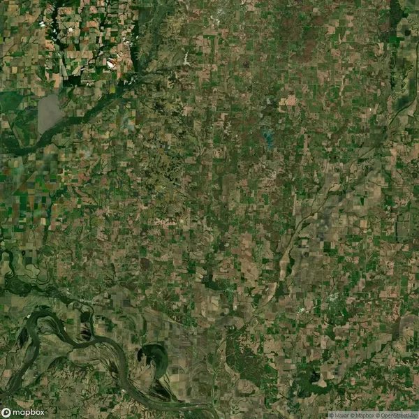 Aerial view of a patchwork landscape with agricultural fields, a river with bends at the bottom, and scattered greenery.