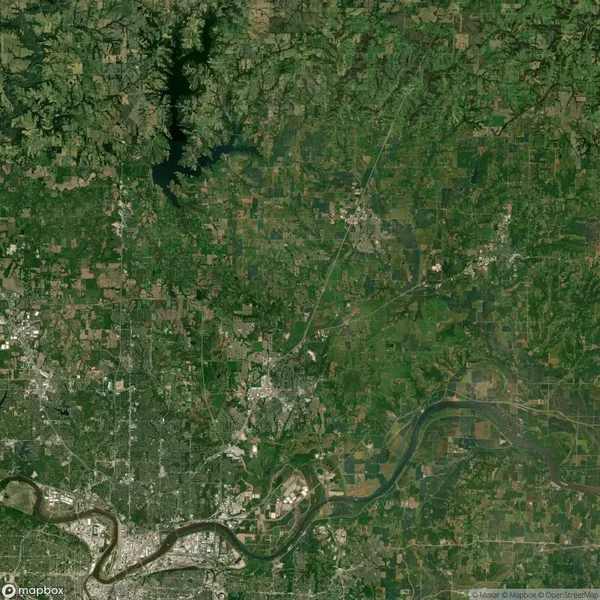 Satellite view of a landscape featuring urban areas, a meandering river, and green forested regions. Roads and patches of farmland are visible, with a large water body in the upper left corner.