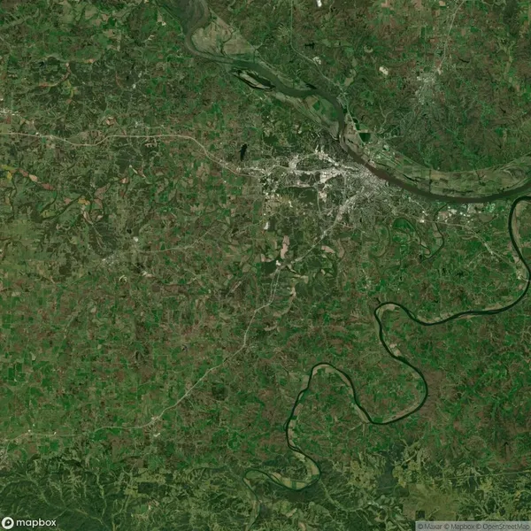 Aerial view of a green landscape with a river winding through it, and a city in the upper right corner.