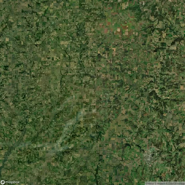 A satellite view of a large green and brown patchwork landscape, showing fields, forests, and rural areas with various land patterns and textures.