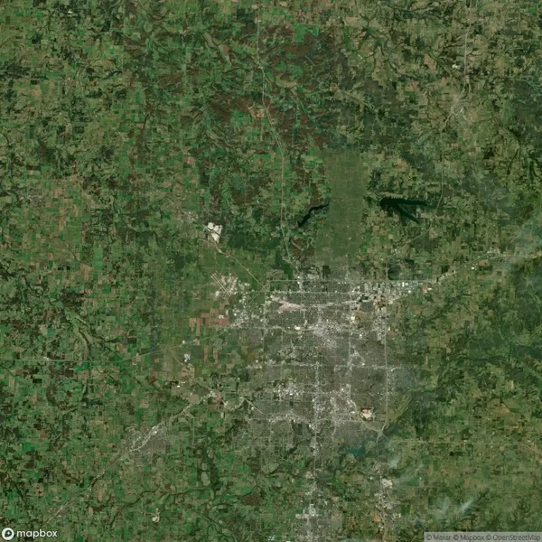 Satellite view showing a landscape with a mix of urban and rural areas, roads, and patches of greenery.