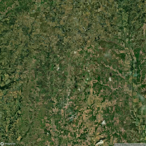 Aerial view of a large geographical area with a patchwork of green and brown fields, roads, and scattered settlements.