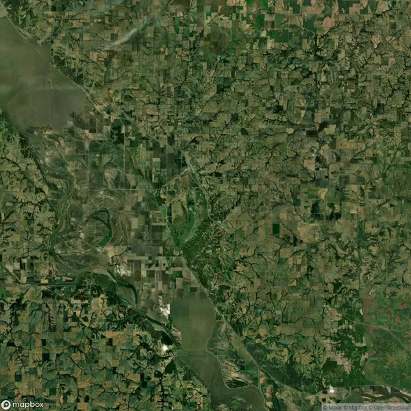 Aerial view of a landscape showing a mix of agricultural fields, patches of forests, and a river running diagonally through the image.