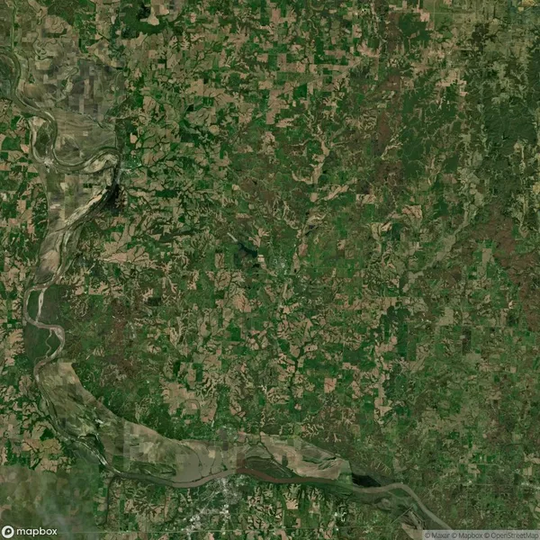 Satellite view of a landscape featuring a river flowing through a mosaic of green and brown patches of land, indicating a mix of vegetation and barren areas.