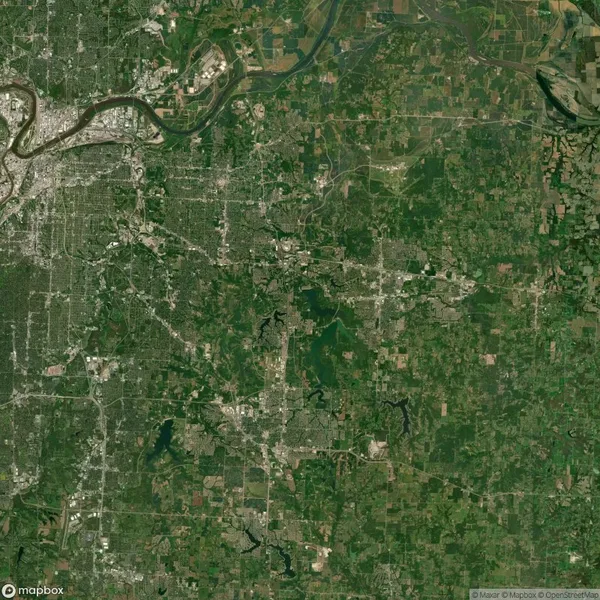Satellite view of a city surrounded by green areas and waterways, showing a mix of urban and rural landscapes. Roads and buildings are visible throughout the image.