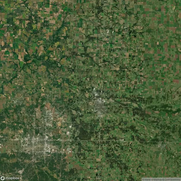 Aerial view of a rural landscape showing a patchwork of green fields and forests, with scattered roads and small towns.