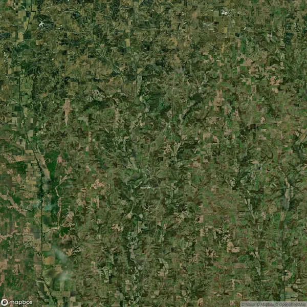 Aerial view of a rural landscape with a patchwork of fields, greenery, and winding roads.