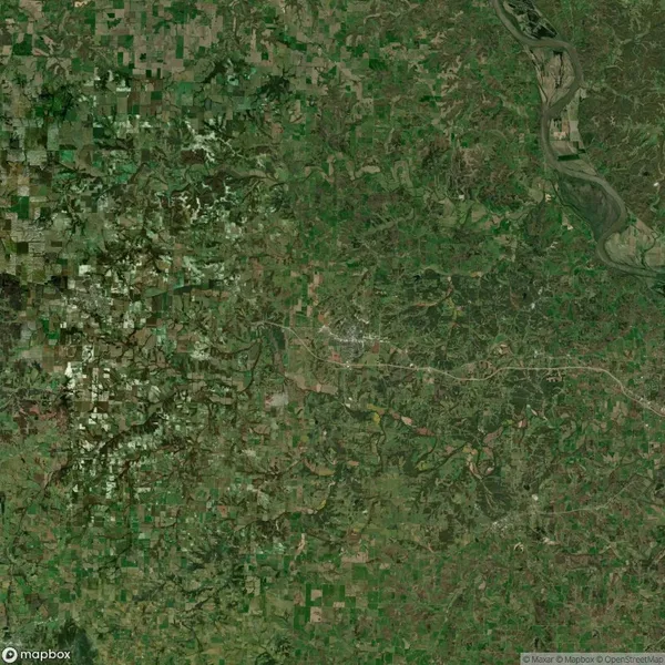 Aerial view of a green and brown patchwork landscape with fields, roads, and a river in the upper right corner.