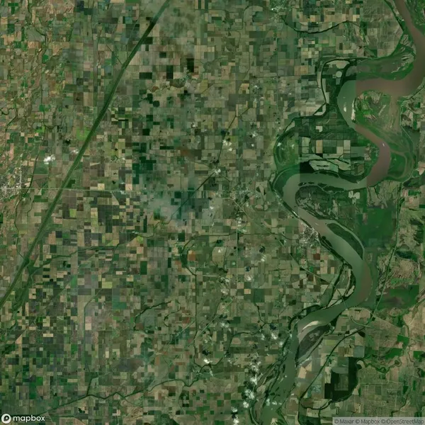 Aerial view of a landscape showing a patchwork of agricultural fields and a winding river, with various shades of green and brown indicating different land uses.